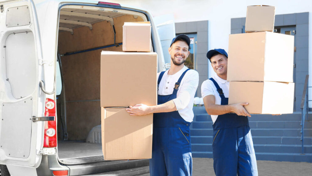  Dwóch mężczyzn trzyma kartony na tle busa i firmy uśmiecha się, ponieważ mają samochód na firmę w Holandii tylko do celów służbowych i mogą skorzystać z różnych odliczeń z tytułu takiego rozwiązania.