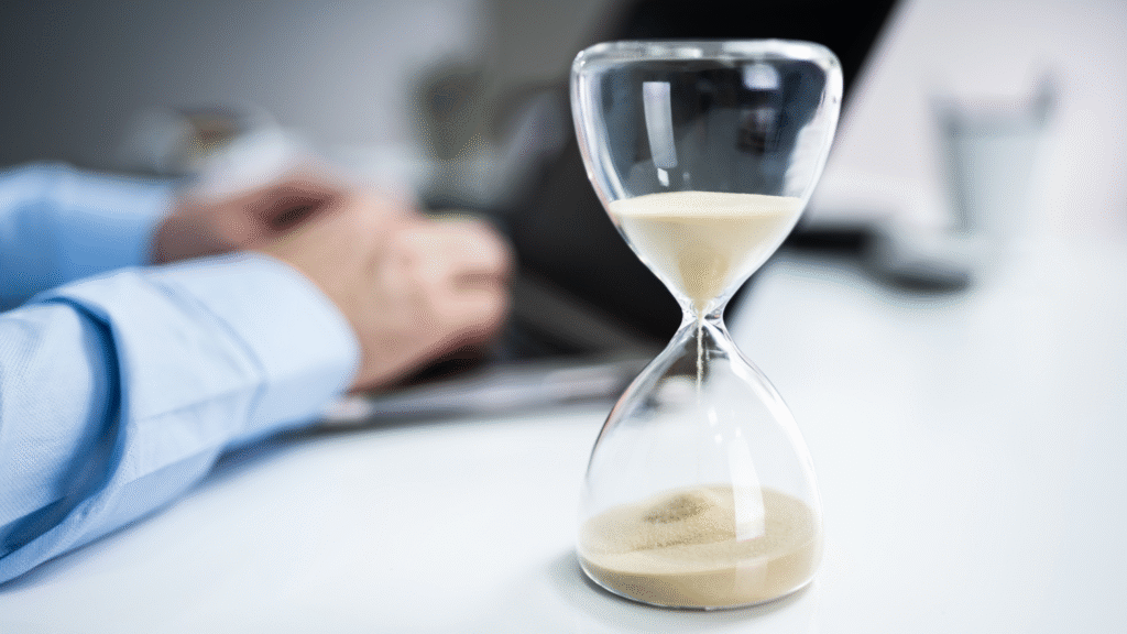 Klepsydra, a w tle mężczyzna pracujący przy laptopie, by spełnić kryterium godzinowe w Holandii.