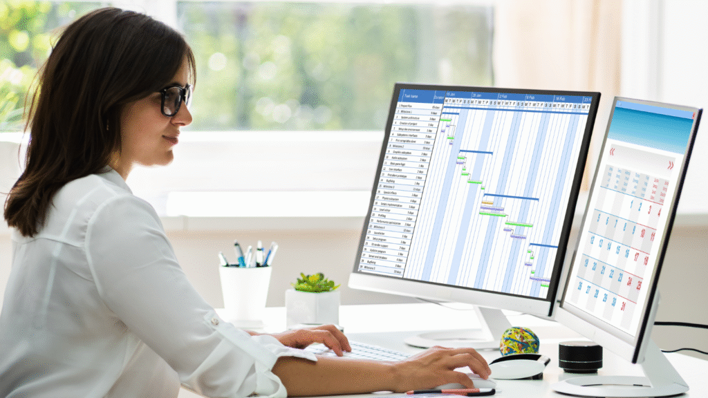 Kobieta pracująca przy dwóch monitorach w trakcie rejestracji czasu pracy, co jest obowiązkowe, by wypełnić limit Urencriterium, czyli kryterium godzinowe w Holandii.